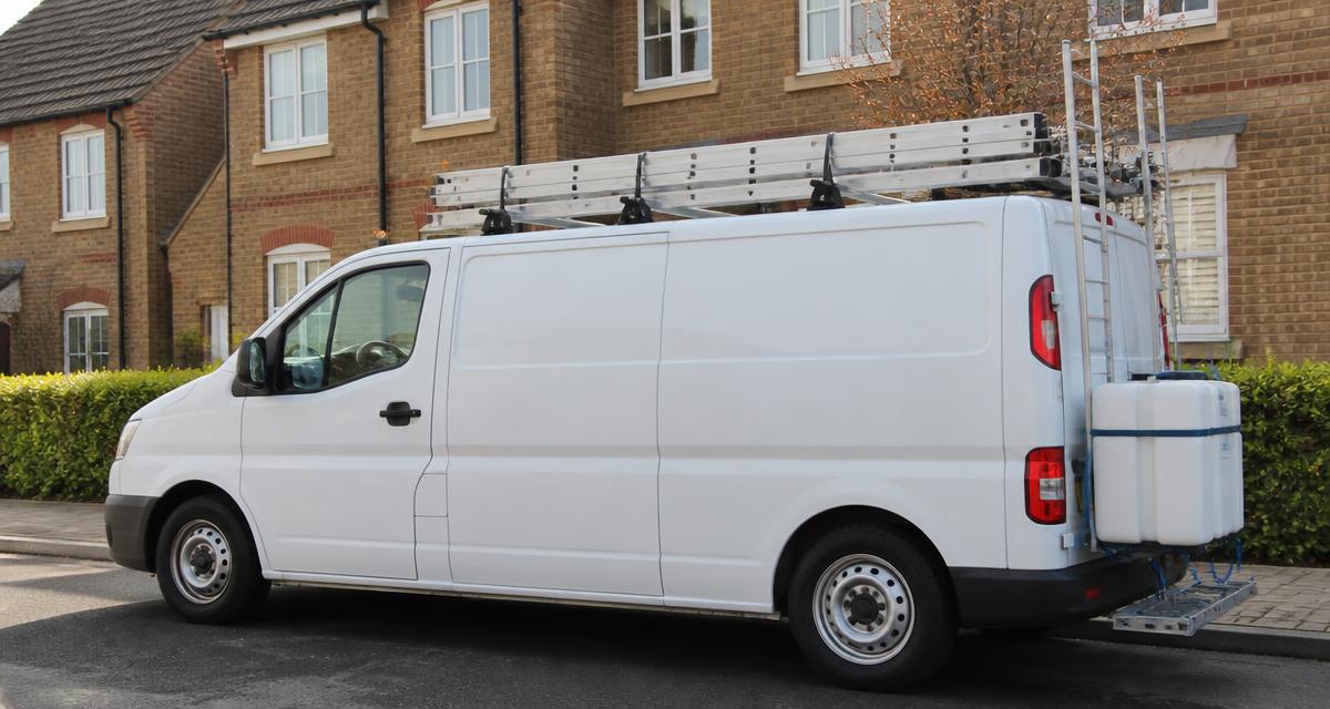 Window cleaning van with roof ladders and water tank parked on a residential street